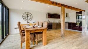 A modern kitchen with dark cabinets, a wooden dining table, and a large wall clock. - 2 Bed in Ipswich (oc-81441) (Witnesham)