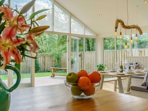 Een moderne keuken met grote ramen, een houten tafel en een schaal met fruit.