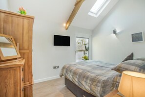 Ein Schlafzimmer mit einem Bett, einem Holzschrank, einem an der Wand befestigten Fernseher und einem Oberlicht.