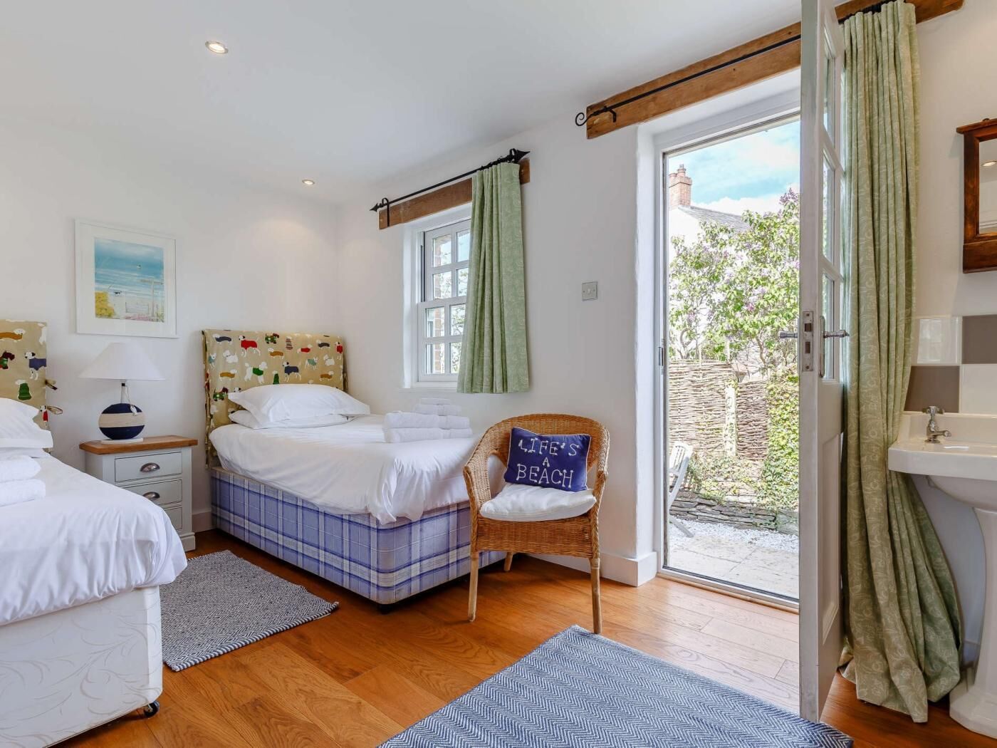 A bedroom with two beds, a chair, a window, a door, and a bathroom.