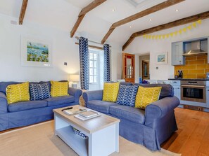 A living room with a sofa set, a coffee table, and a kitchen area with modern appliances. - 2 Bed in Wadebridge (oc-82682) (Little Petherick)