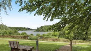 Ein Park mit einer Bank, einem Holenzaun und einem See.