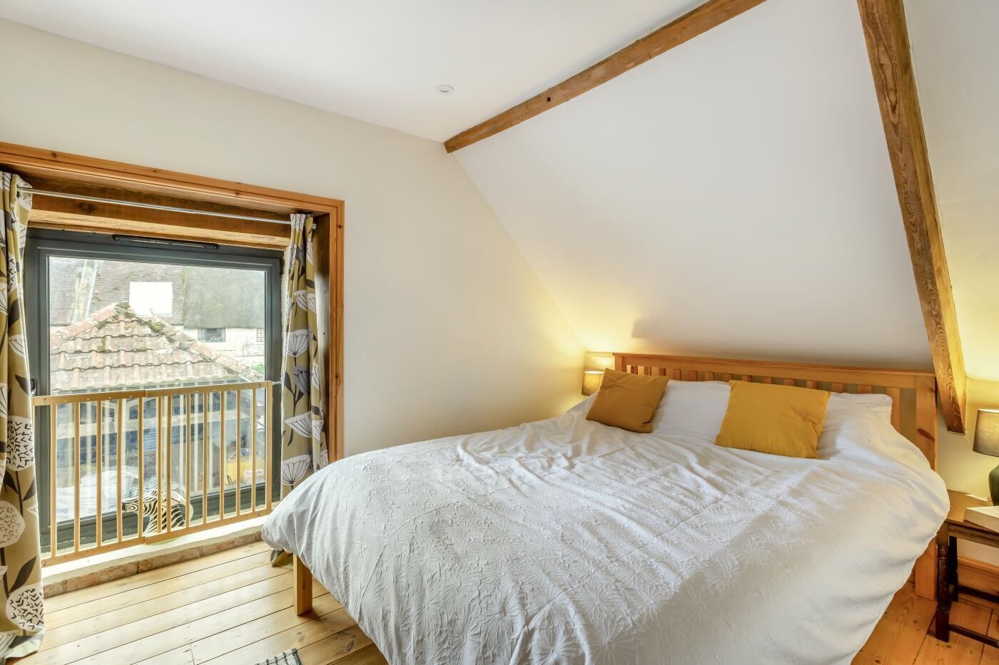 A bedroom with a large bed, a window with curtains, and a wooden ceiling.