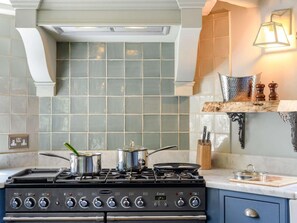 A kitchen with a gas stove, pots, a backsplash, and a wooden shelf with kitchen utensils. - 4 Bed in Salisbury (oc-82799) (Winchester)