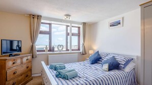 Un dormitorio con una cama, televisión, cómoda y ventana con vistas.