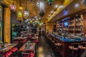 Ein Restaurant mit mehreren Tischen und Stühlen, einer Bar mit einer Theke und dekorativen Laternen.