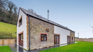 A modern house with a stone facade, large windows, and a sloped roof. - 3 Bed in Ilfracombe (oc-82866) (Combe Martin)