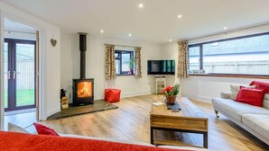 A living room with a fireplace, a sofa, a TV, and a window. - 3 Bed in Ilfracombe (oc-82866) (Combe Martin)