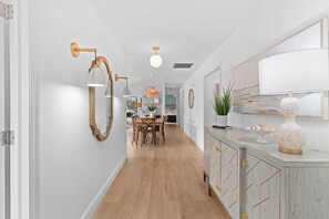 A hallway with a dining area, wooden cabinets, and a large mirror. - Renovated Naples Home l Near Vanderbilt Beach (Naples)