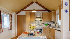 Eine Küche mit Holzausstattung, einer karierten Tischdecke und einem Esszimmerstuhl.