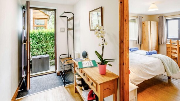 A bedroom with a bed, a desk with a chair, a small table with a plant, and a window with curtains. - 3 Bed in Todmorden (oc-82953) (Todmorden)