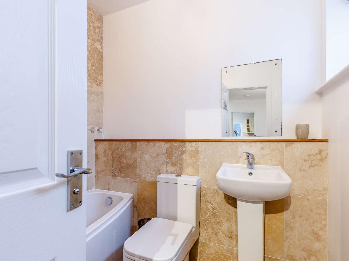 A bathroom with a bathtub, toilet, sink, and a mirror above the sink.