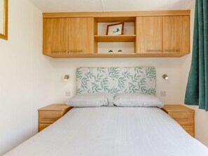 Ein Schlafzimmer mit einem Bett, Holzschränken darüber und einem an der Wand befestigten Regal mit einem Bild.