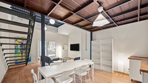 A modern interior with a white table, chairs, a TV, and a staircase. - Barrio Sanctuary - Bosque Azul (San Juan)