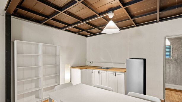 A modern kitchen with white cabinetry, a wooden countertop, and a pendant light. - Barrio Sanctuary - Bosque Azul (San Juan)