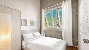 A bedroom with a bed, a wardrobe, a window with curtains, and a wall with a drawing. - Barrio Sanctuary - Bosque Azul (San Juan)