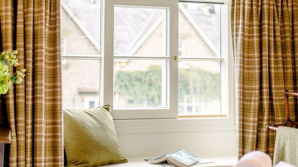 Ein Zimmer mit Fenster, Bett, Kissen und einem Buch.