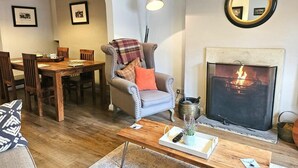 Ein gemütliches Wohnzimmer mit Kamin, einer Essecke mit Holzmöbeln und einer komfortablen Sitzecke.