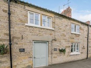 A stone cottage with a white door, two windows, and a small sign indicating 'Lavender Cottage'. - 3 Bed in Helmsley (oc-82891) (Helmsley)