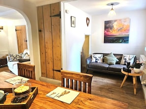 Een gezellige woonkamer met een houten eettafel, een bank en een bijzettafeltje.