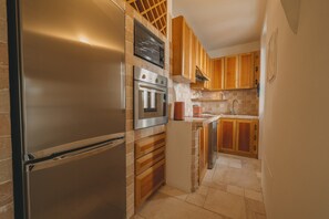 Eine moderne Küche mit Edelstahlgeräten, Holzschränken und einer gefliesten Rückwand.