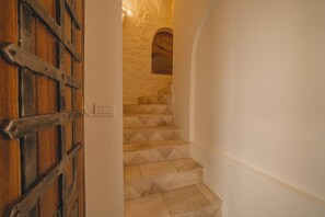 Eine Treppe mit Steinstufen führt zu einer Empore mit einer Holztür.