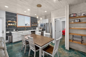 A modern kitchen with white cabinetry, a wooden dining table, and pendant lighting. - Old Town Oasis Rooftop Deck - Pool - Walk to Everything! (Port Aransas)