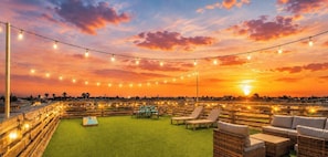 A rooftop terrace with string lights, outdoor furniture, and a sunset view. - Old Town Oasis Rooftop Deck - Pool - Walk to Everything! (Port Aransas)