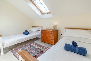 A bedroom with a skylight, two single beds, a wooden dresser, and a patterned rug. - 5 Bed in Truro (oc-tc82928) (Mount Hawke)