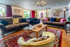 A spacious living room with leather sofas, a coffee table, and a patterned rug. - 5 Bed in Truro (oc-tc82928) (Mount Hawke)