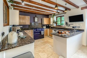 A kitchen with granite countertops, wooden cabinets, a built-in oven, a sink, and a window with a view of greenery. - 5 Bed in Truro (oc-tc82928) (Mount Hawke)