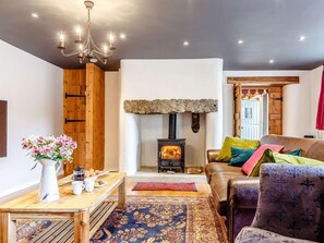 Ein gemütliches Wohnzimmer mit Kamin aus Stein, Holzmöbeln und einer Chandelüster.