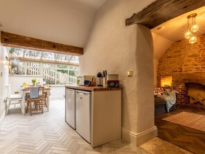 A kitchen with a built-in dishwasher, a dining area with a table and chairs, and a stone fireplace. - 3 Bed in Belper (oc-83037) (Blackbrook)