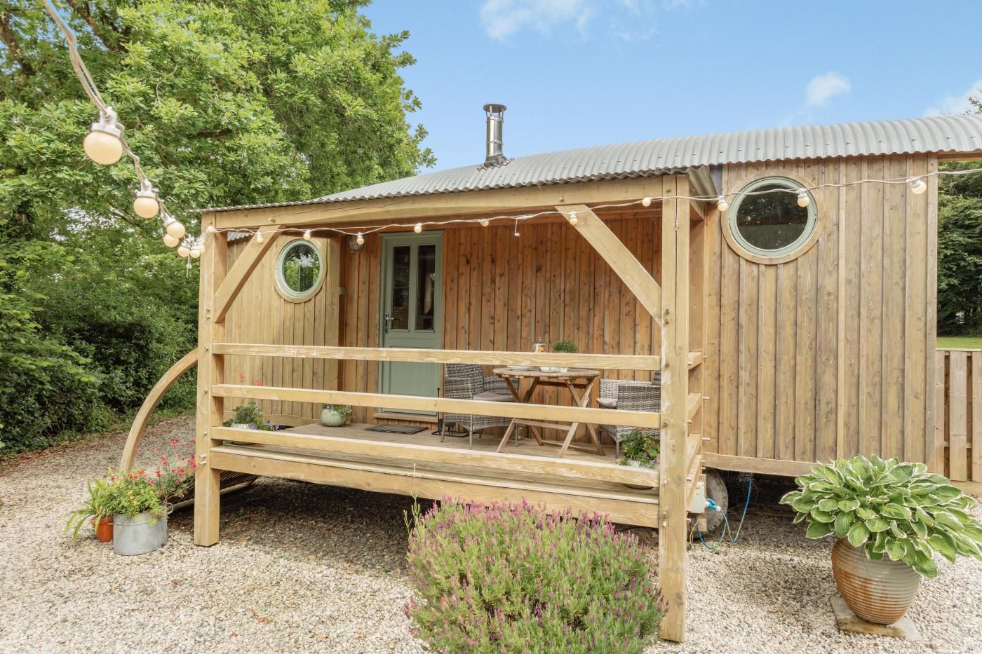 Eine Holzhütte mit Veranda, einem Esstisch und zwei Rundfenstern.
