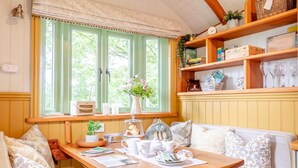 Um quarto aconchegante com uma mesa de madeira, um banco e uma janela com cortinas.