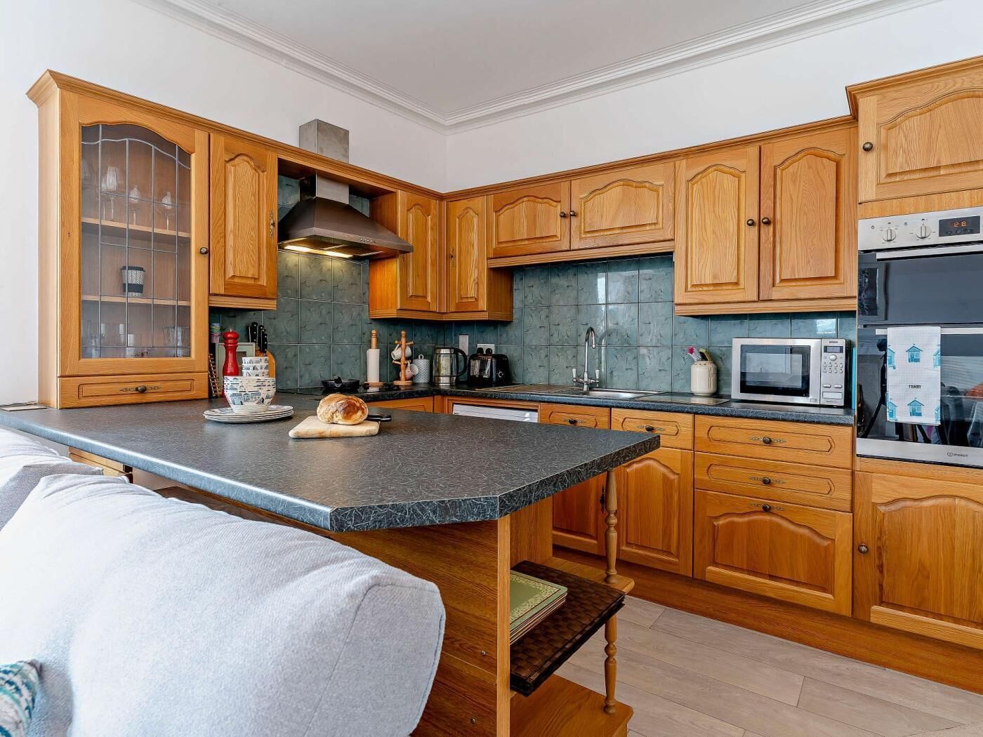 Une cuisine moderne avec des meubles en bois, un plan de travail en marbre, des appareils électrom énagers en acier inoxydable et un four encastré.
