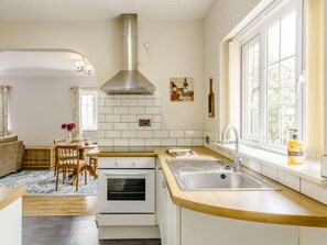A modern kitchen with white cabinetry, a stainless steel range hood, a built-in oven, a wooden countertop, and a window with a view of greenery. - 1 Bed in Aberdare (oc-82906) (Merthyr Tydfil)