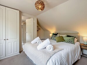 Ein Schlafzimmer mit einem großen Bett, einem Kleiderschrank, einer Tür und einer Pendelleuchte.