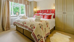 Een slaapkamer met een bed, een raam met gordijnen, een wandlamp en een kledingkast.