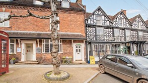 A traditional British pub with a Tudor-style facade, a red telephone booth, and a parked car on the street. - 1 Bed in Kidderminster (oc-82957) (Cleobury Mortimer)