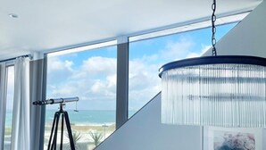 Ein modernes Zimmer mit großem Fenster, einem Teleskop und einer Chandelüster.
