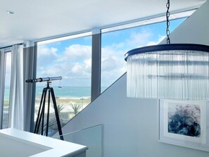 A modern room with a large window, a telescope, and a chandelier. - 4 Bed in Newquay (oc-83117) (Newquay)