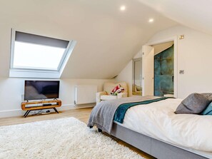 A bedroom with a skylight, a television, a bed, a chair, and a radiator. - 4 Bed in Newquay (oc-83117) (Newquay)