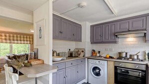 Une cuisine moderne avec des meubles gris, un lave-linge encastré et une cuisinière.