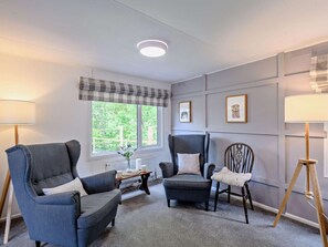 A room with two armchairs, a small table, and a window with a view of greenery.