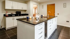 Une cuisine moderne avec des meubles blancs, un plan de travail noir et un îlot central.