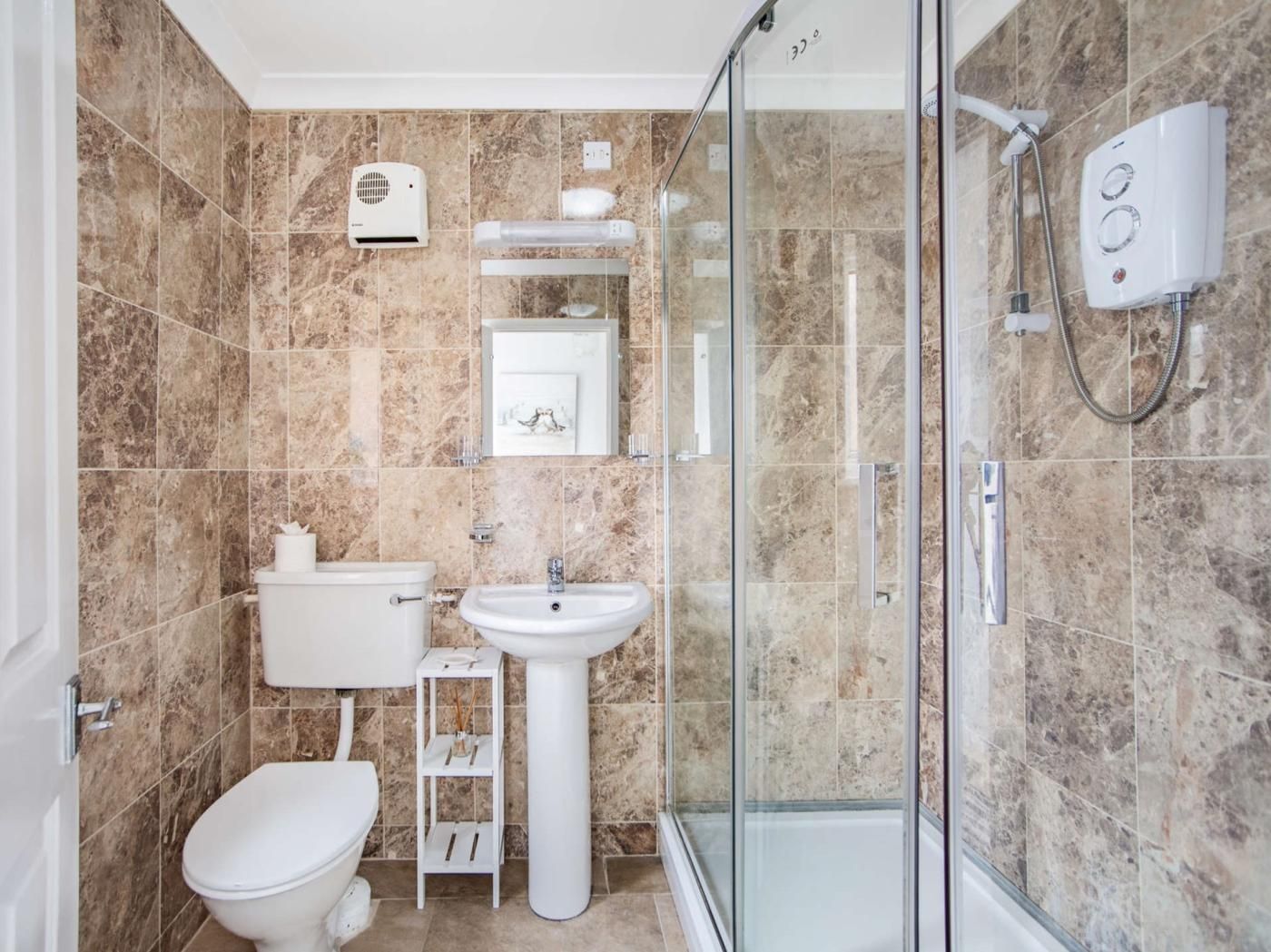 Ein Badezimmer mit Toilette, Waschbecken, Dusche und einer Duschkabine aus Glas.