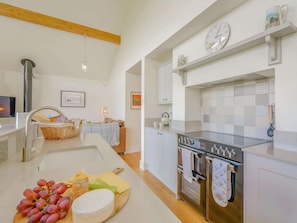 Una cocina moderna con horno empotrado, un lavamanos y una encimera con frutas y queso.