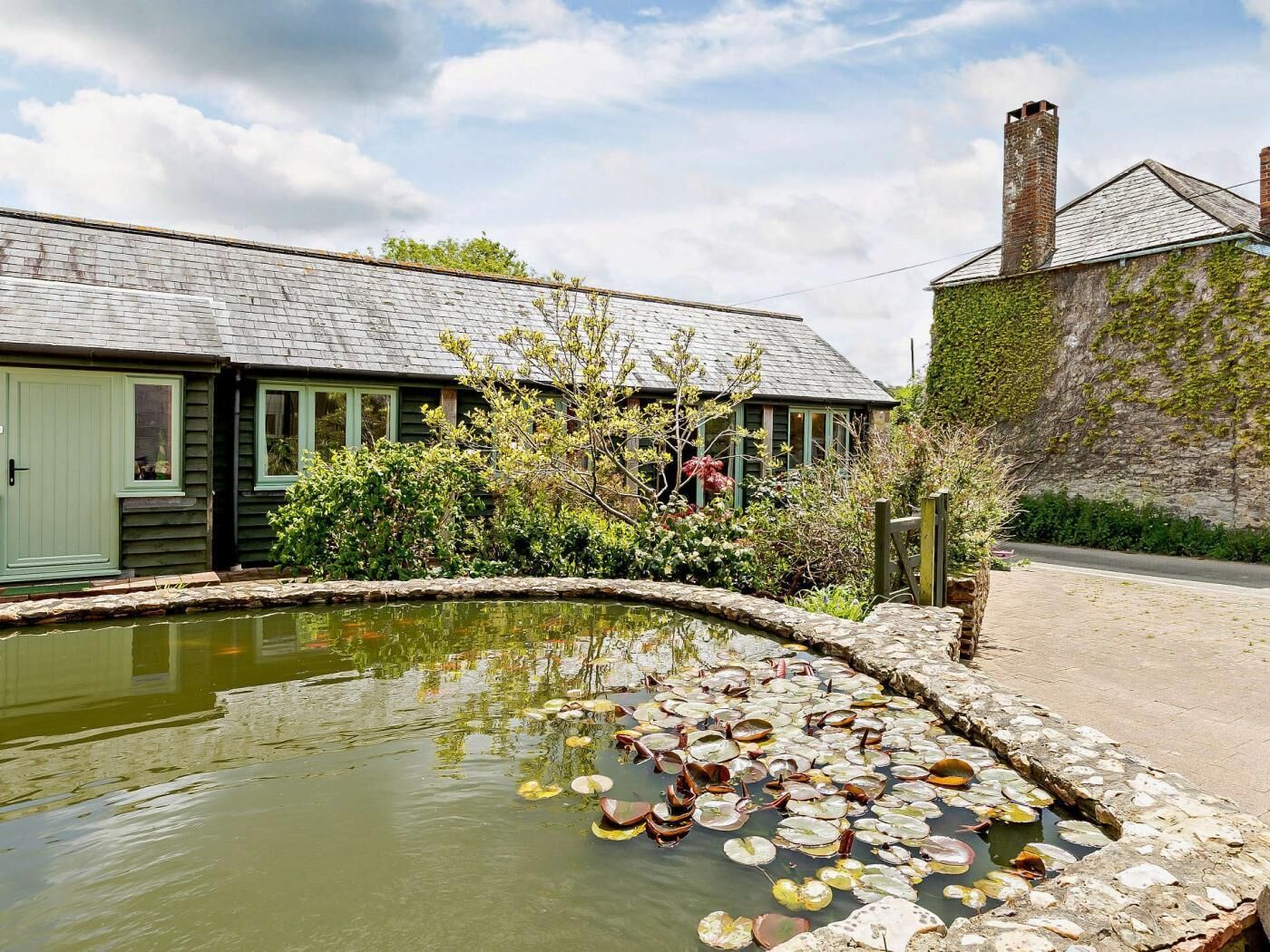 A traditional building with a pond, stone pathway, and a rustic chimney.