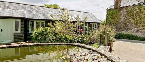 A traditional building with a pond, stone pathway, and a rustic chimney.